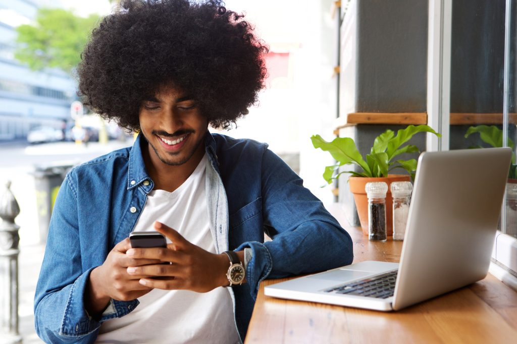 young adult with an afro accesses meta business manager on his phone and laptop for his cannabis business